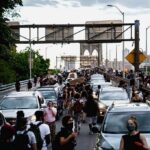 Crowd of protesters walking among cars on a city bridge
