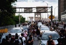 Crowd of protesters walking among cars on a city bridge