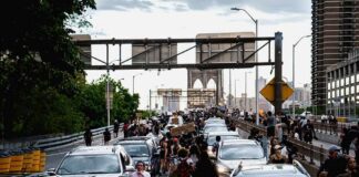 Diesel Surge Lights Cities On Fire Crowd of protesters walking among cars on a city bridge