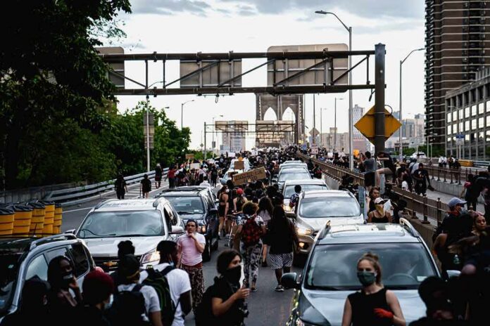 Crowd of protesters walking among cars on a city bridge