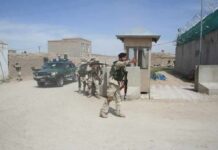 Armed soldiers patrol near a guard post outside a walled compound