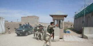 Armed soldiers patrol near a guard post outside a walled compound