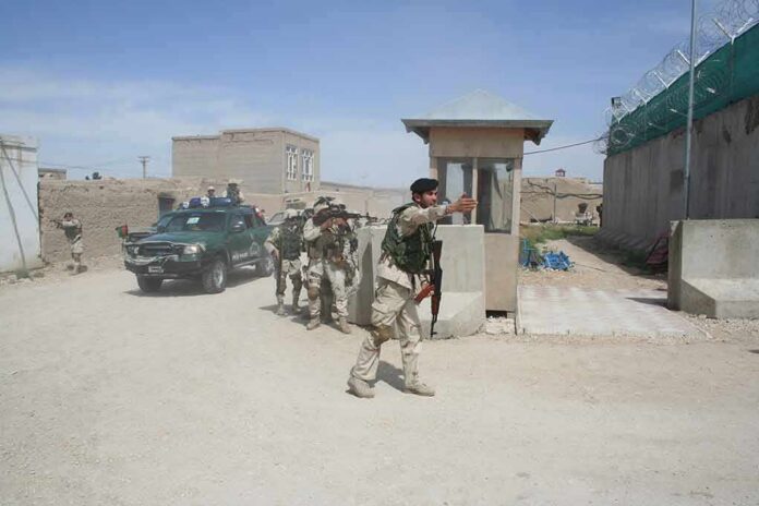 shutterstock_1931171399 Armed soldiers patrol near a guard post outside a walled compound