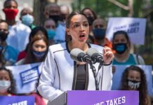 Woman speaking at outdoor podium with microphones