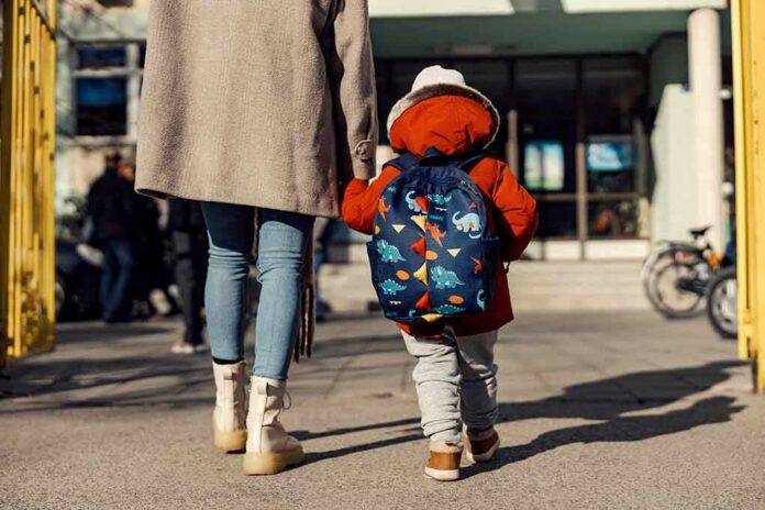 Child with backpack walking to school with adult