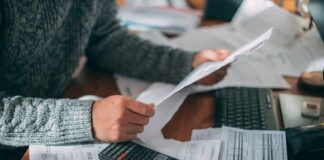Person reviewing bills with calculator at cluttered desk