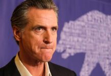 Gavin Newsom at a press event with a purple backdrop