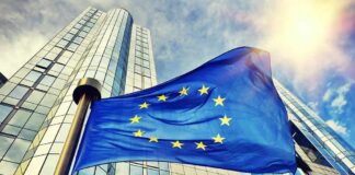 EU – Canada Gambit Triggers Tariff Warning European Union flag waving in front of modern glass office buildings