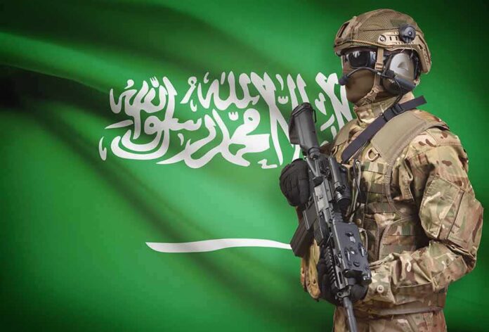Soldier in tactical gear stands before a green flag