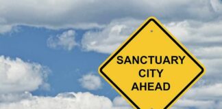 Sanctuary Clash Sparks Capitol Firestorm yellow road sign with sanctuary city message against cloudy sky