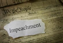 Clock-Stopping Move Freezes Impeachment Torn paper with the word impeachment on the U.S. Constitution