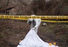 forensic investigator at outdoor crime scene behind caution tape