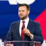 man in suit speaking at a podium