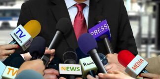 TV Giants Accused Of Illegal Boycott Press microphones surround a suited spokesperson
