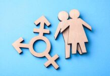 Texas Opens The First Detransition Clinic Wooden transgender symbol and two human figures on blue background