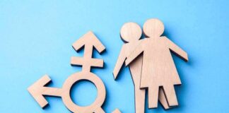 Texas Opens The First Detransition Clinic Wooden transgender symbol and two human figures on blue background