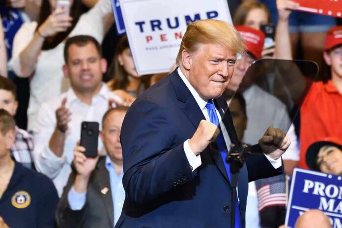 shutterstock_1148319815 Donald Trump at a rally raising his fists on stage