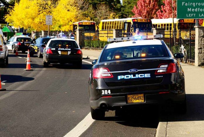 Police cars with lights on near school buses on a city street