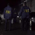 FBI agents at a nighttime crime scene beside ambulance and car