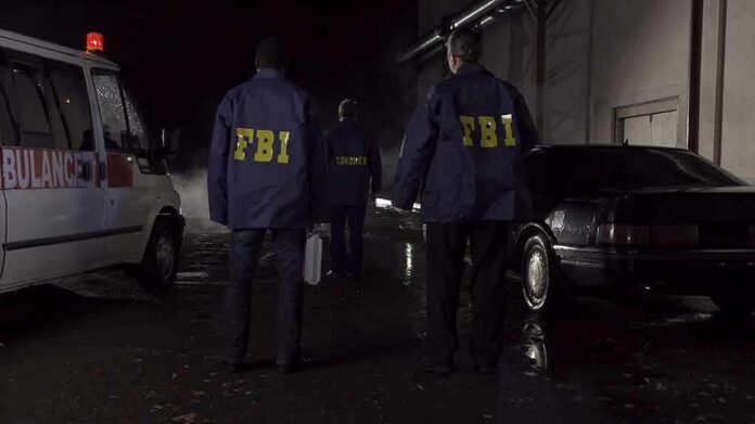 FBI agents at a nighttime crime scene beside ambulance and car