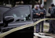 Car door with bullet holes at a taped-off crime scene