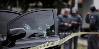 Car door with bullet holes at a taped-off crime scene