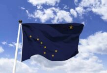 DOJ: Alaska Misleading Its Own Voters Alaska state flag waving on a pole against a blue sky