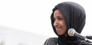 Omar Answers Questions After Federal Home Search Ilhan Omar speaking at a microphone with hand on chest