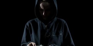 Person in a hoodie counting cash in low light