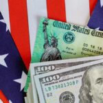 U.S. Treasury check and hundred dollar bills on American flag