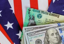 U.S. Treasury check and hundred dollar bills on American flag