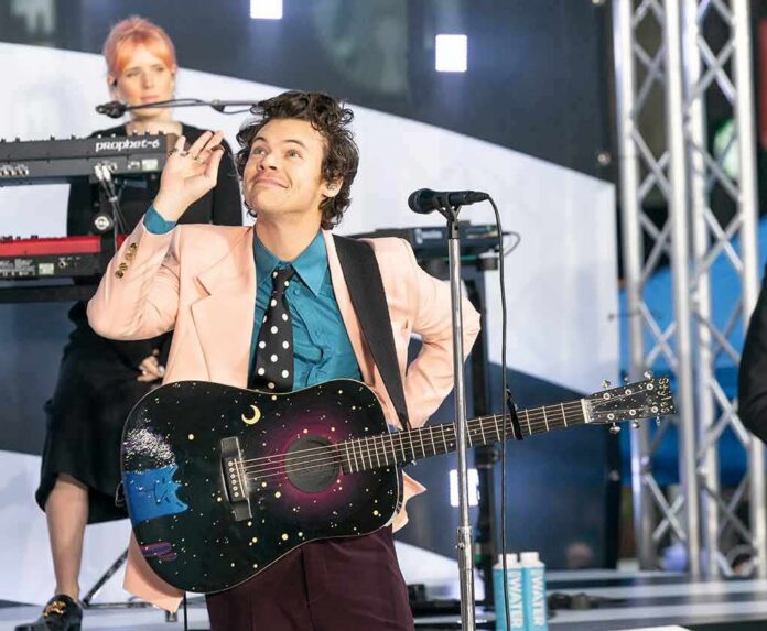 shutterstock_1656961513 Harry Styles performing on stage with a decorated acoustic guitar