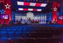 Missing Transcript Fuels Racism Uproar Debate stage with red and blue lighting and empty audience seats
