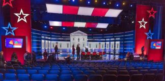 Missing Transcript Fuels Racism Uproar Debate stage with red and blue lighting and empty audience seats