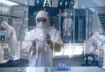 Scientist in hazmat suit using a transparent digital tablet in a lab
