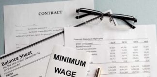 Minimum wage note on financial documents with glasses and pen