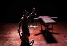Court Whiplash as Inmate Keeps Breathing Lady Justice statue with scales in dramatic light beside an empty gurney