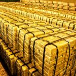 Stacks of gold bars strapped together in a vault