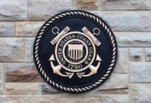 Coast Guard Nabs Crowded Mystery Boat Bronze emblem of the United States Coast Guard mounted on a stone wall