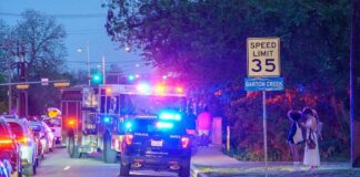 Gunfire Shocks Packed Homecoming Emergency vehicles with flashing lights on a city street at night