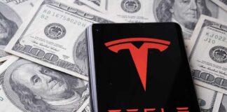 Tesla logo on smartphone over US hundred-dollar bills