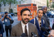 Beloved NYC Icon Targeted For Extinction Zohran Mamdani speaking to reporters on a city sidewalk