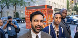 Beloved NYC Icon Targeted For Extinction Zohran Mamdani speaking to reporters on a city sidewalk