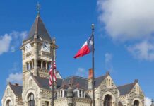 Payroll Phantom Scheme Rattles Texas Historic stone courthouse with clock tower and flags