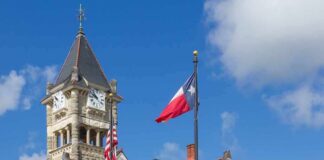 Historic stone courthouse with clock tower and flags