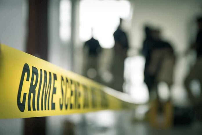 shutterstock_579245569 Crime scene tape with investigators in the background