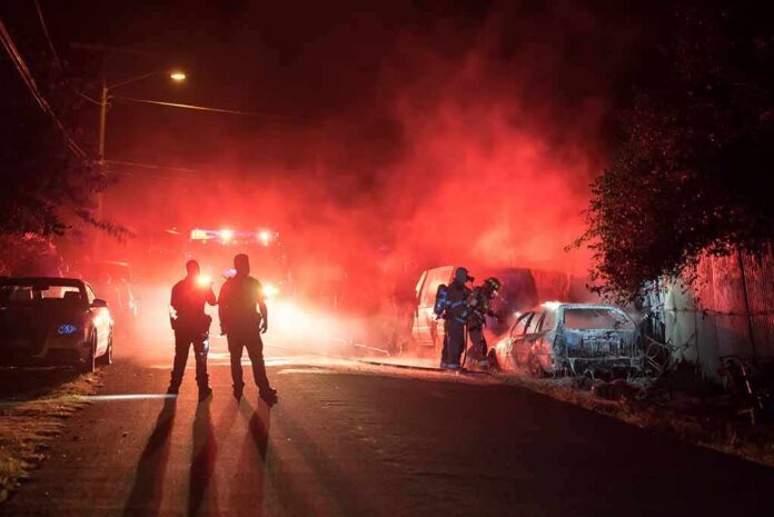 shutterstock_680019202-1 Firefighters and police at a nighttime car fire scene
