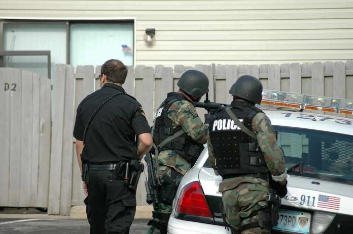 shutterstock_728435 police officers in tactical gear beside patrol car